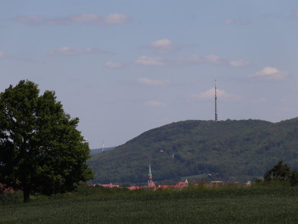 Blick auf eine Bergkuppe mit Fernsehturm, im Vordergrund eine Stadt 